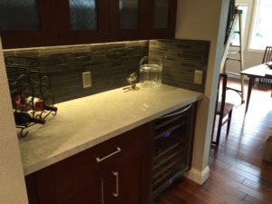 Wet bar with mosaic backsplash and under-cabinet lighting